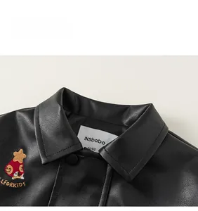 Detail of kids black faux leather jacket featuring colorful embroidered patches and lapels