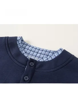 Detail of boys' navy knit sweater with a blue plaid faux two-piece collar and buttons