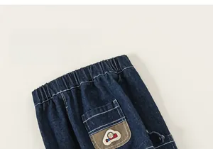 Detail of kids denim cargo pants showing elastic waistband and baseball embroidery pocket