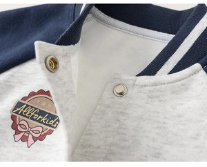 Close-up of kids baseball jacket with metallic snap buttons and embroidered logo detail