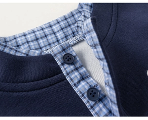 Detail of navy blue knit top collar with blue and white plaid lining and durable buttons