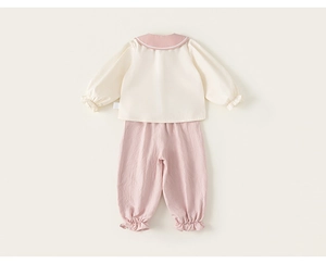 Detail of baby girl outfit featuring a cream shirt with pink collar and matching trousers