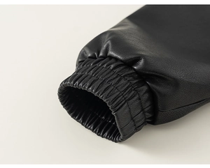 Detail shot of elastic cuffs on black faux leather jacket showing lychee grain texture