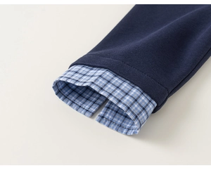 Detail of navy boy's sweatshirt with fake two-piece plaid shirt cuff and soft texture
