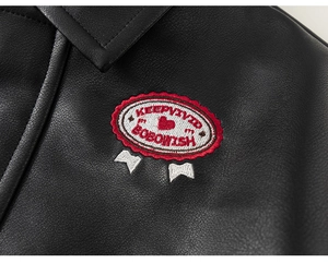 Detail of children's black faux leather jacket featuring vintage heart embroidery patch