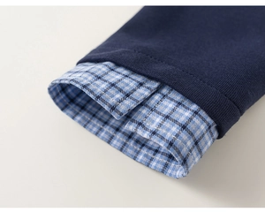 Detail of navy sweatshirt with blue and white checkered shirt cuffs in fake two-piece style