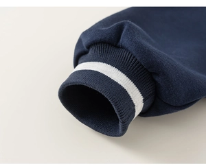 Detailed close-up of dark blue ribbed cuffs with white stripes on a kid's baseball jacket