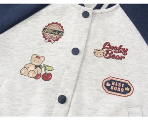 Close-up of girls' varsity jacket with cartoon patches and contrast snap buttons