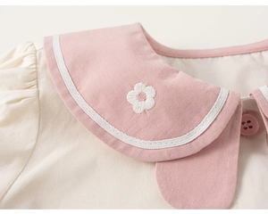 Detail of baby doll collar with flower embroidery and contrast stitching on beige top