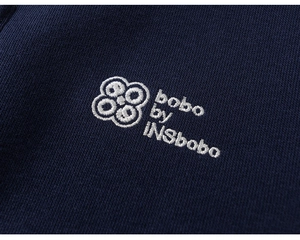 Macro detail of white logo embroidery on navy blue knit cotton boys clothing fabric