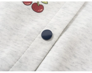 Macro detail of kids baseball jacket showing grey knit fabric, cherry print, and snap button
