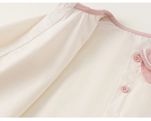 Detail of pink piping and round buttons on a white Peter Pan collar girl shirt