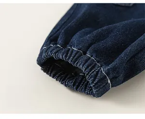 Detailed close-up of elastic ribbed cuffs on dark blue denim pants with white double stitching