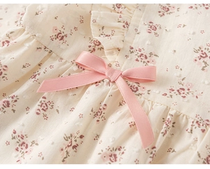 Dettaglio vestito neonata a fiori con trama a pois 3D, fiocco rosa e bordi a balze