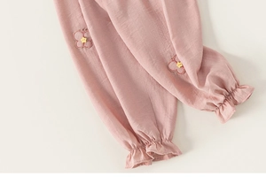 Detail of pink cotton trousers with butterfly embroidery and star button on ruffle hem