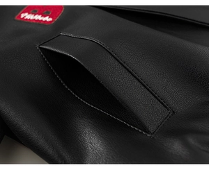 Close-up of black faux leather jacket texture with red decorative label and pocket stitching