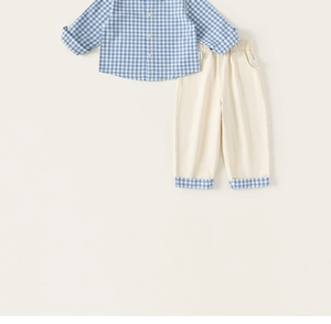 Detail of boys' plaid cotton shirt with matching beige pants and checkered cuff accents