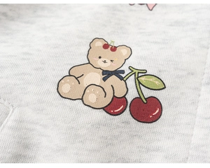 Detail of grey kids baseball jacket featuring a cute bear and cherry graphic print