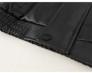 Detail of kids black leather jacket featuring elastic hem and snap button closure