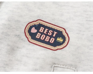 Macro shot of embroidered BEST BOBO patch on gray knit girls' baseball jacket