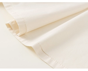Close-up of fine stitching and soft cream fabric texture on children's clothing hem