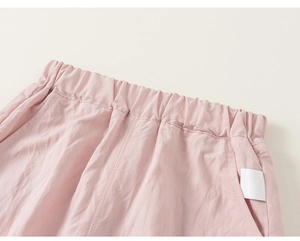 Detail of pink cotton trousers showing elastic waistband and side pocket texture