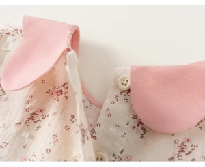 Dettaglio del colletto Peter Pan rosa e motivo floreale su vestito a maniche lunghe bimba
