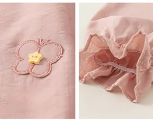 Detail of pink cotton trousers featuring butterfly embroidery and elastic ruffled cuffs