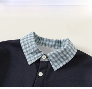 Détail du polo pour garçon en tricot bleu marine avec col à carreaux et boutons blancs