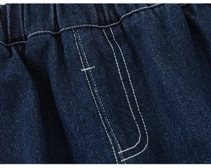 Detail of elastic waistband on dark blue boys' jeans with white contrast stitching