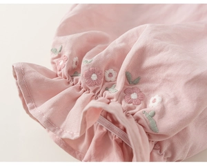 Detail of pink cotton sleeve with floral embroidery and ruffled elastic cuff design