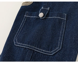 Close-up of deep blue denim texture with white contrast stitching and metal button detail