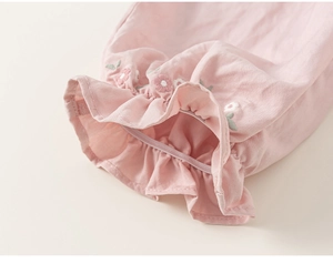 Detailed close-up of pink sleeve with floral embroidery and ruffled elastic cuff