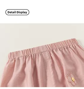 Detail of pink cotton trousers with elastic waistband and butterfly floral patch