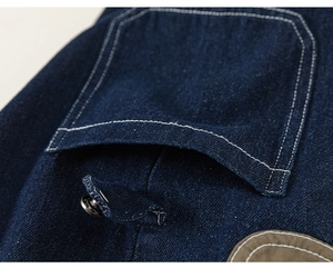 Detailed close-up of dark blue denim cargo pocket with white contrast stitching and snap button