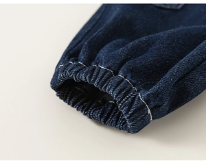 Detailed close-up of dark blue denim jeans with elastic cuffs and white contrast stitching