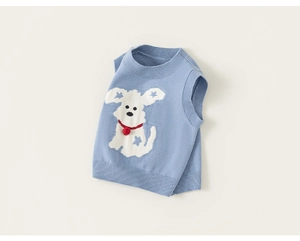 Detail of blue knitted toddler vest featuring white dog pattern and 3D red pom-pom tie