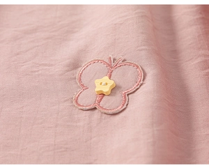 Detailed macro shot of pink cotton fabric with butterfly embroidery and star button