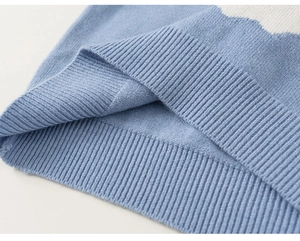 Macro detail of baby boy knit vest showing ribbed hem and blue cloud pattern texture