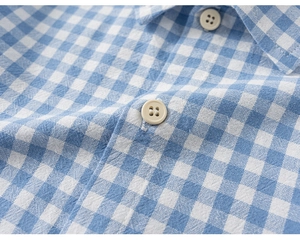 Detailed close-up of blue gingham cotton shirt fabric with premium white resin buttons