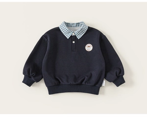 Détail d'un sweat bleu marine pour enfant avec col à carreaux et badge brodé sur le buste