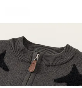 Detailed macro view of dark grey knit sweater with black star patterns and leather zipper puller