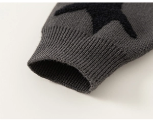 Detail of grey knitted sleeve cuff with a black plush star patch and ribbed texture