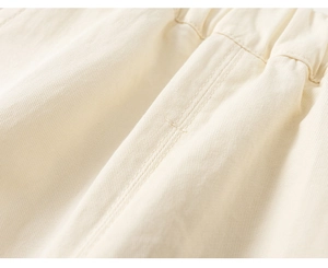 Detailed close-up of elastic waistband with reinforced stitching on beige twill trousers