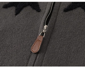 Detail of grey knitted jacket with black star patterns and leather zipper puller