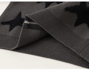 Detail of dark grey knit jacket with black star pattern and silver metal zipper closure