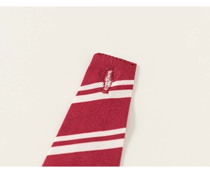 Détail de la cravate bordeaux avec rayures blanches et finitions précises de la boutonnière