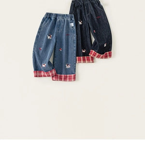 Dettaglio di pantaloni in denim per bambini con ricami e risvolti a quadri rossi