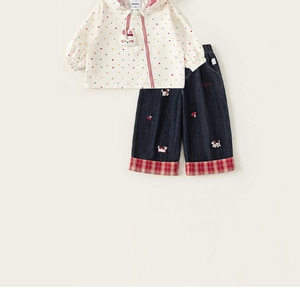 Detail of girls' cream jacket with colorful polka dots and denim pants with embroidery