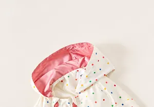 Detail of hooded kids jacket with colorful polka dots and soft pink lining fabric